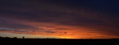 Very wide sunset panorama with bright red against dark purple clouds.