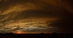 Curved clouds and red glow of the setting sun.